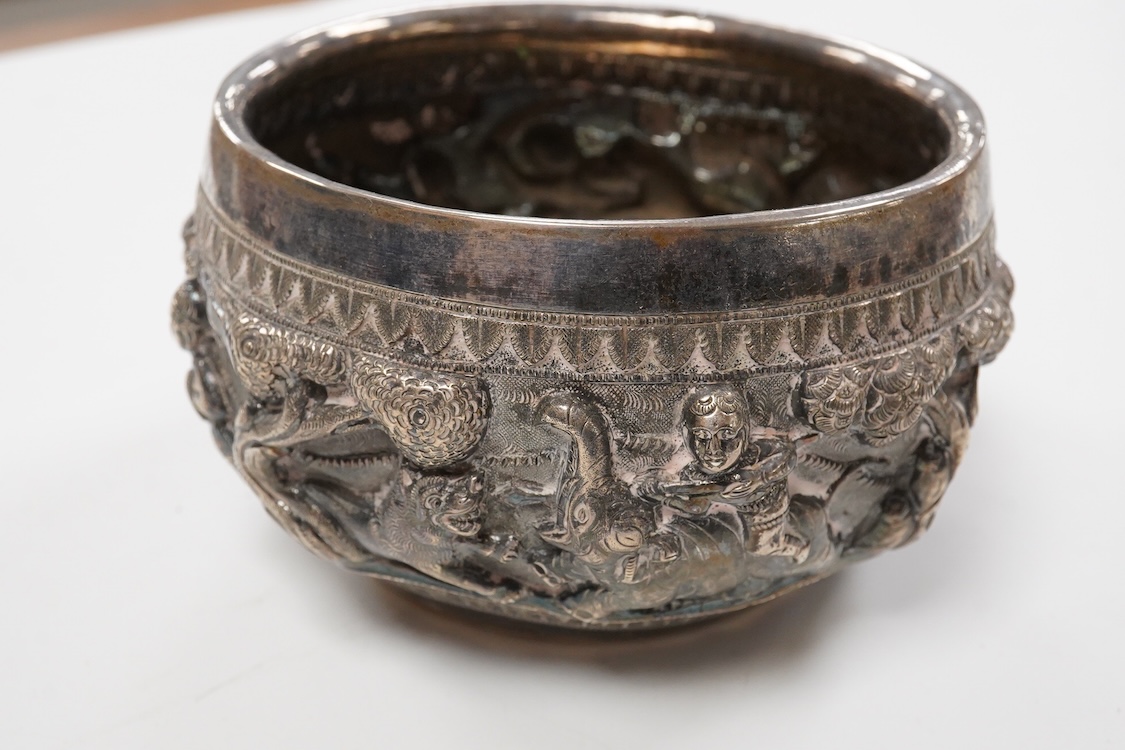 A late 19th/early 20th century Burmese white metal bowl, embossed with figures and animals in continuous battle scene, top diameter 12.4cm.